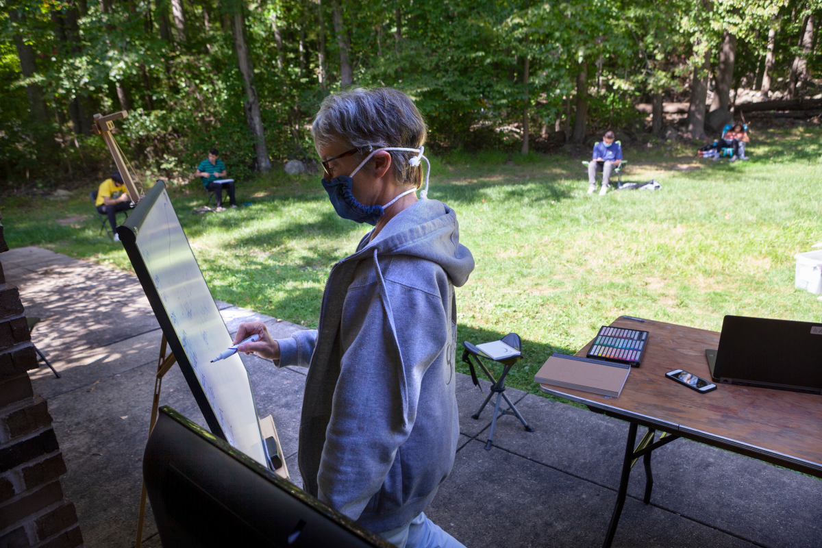 Maggie, the PLC art teacher, at the white board, outside, during Art class